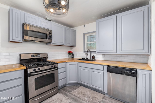 kitchen with wooden counters, sink, appliances with stainless steel finishes, and hardwood / wood-style floors