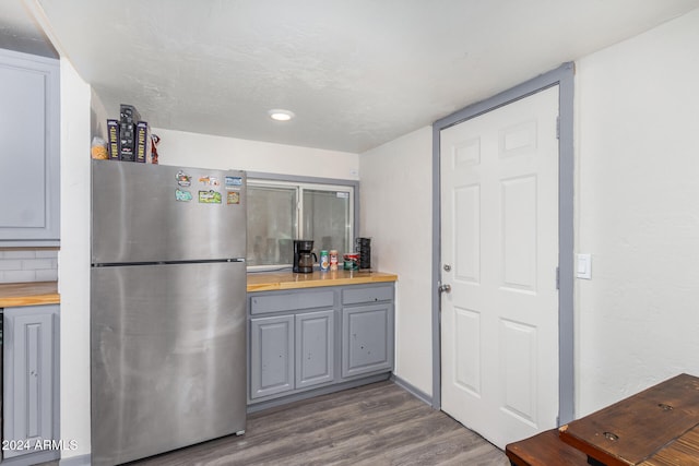 kitchen featuring wood counters, tasteful backsplash, dark hardwood / wood-style floors, and stainless steel fridge