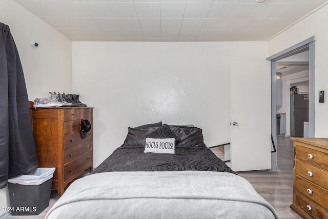 bedroom with stainless steel fridge and dark hardwood / wood-style flooring