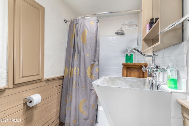 bathroom featuring sink, wooden walls, and a shower with shower curtain