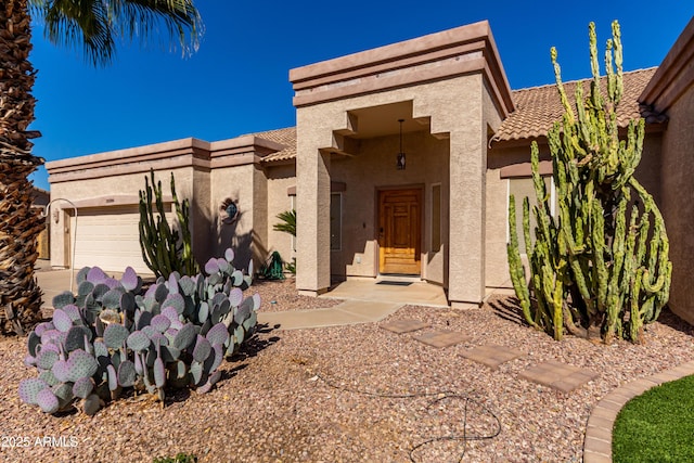 view of front facade with a garage, a tile roof, and stucco siding