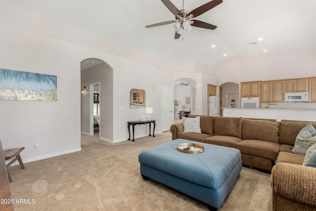 living room featuring arched walkways, baseboards, a ceiling fan, and light colored carpet