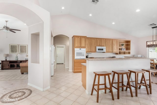 kitchen with white appliances, arched walkways, hanging light fixtures, light countertops, and ceiling fan with notable chandelier