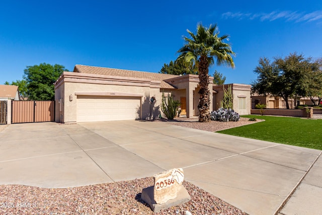 view of front of house featuring driveway, an attached garage, a gate, fence, and stucco siding