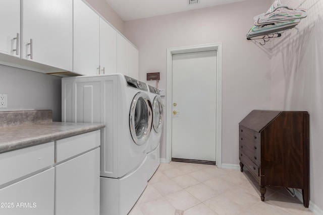 washroom featuring light tile patterned floors, separate washer and dryer, visible vents, baseboards, and cabinet space