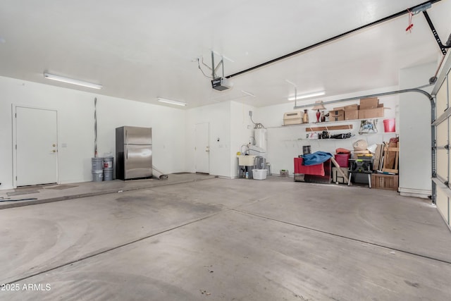 garage featuring water heater, a garage door opener, and freestanding refrigerator