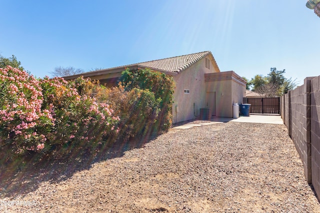 view of home's exterior with cooling unit, a gate, fence, and stucco siding