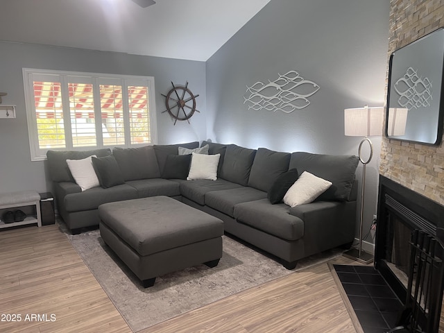 living room with hardwood / wood-style flooring, a tile fireplace, and vaulted ceiling