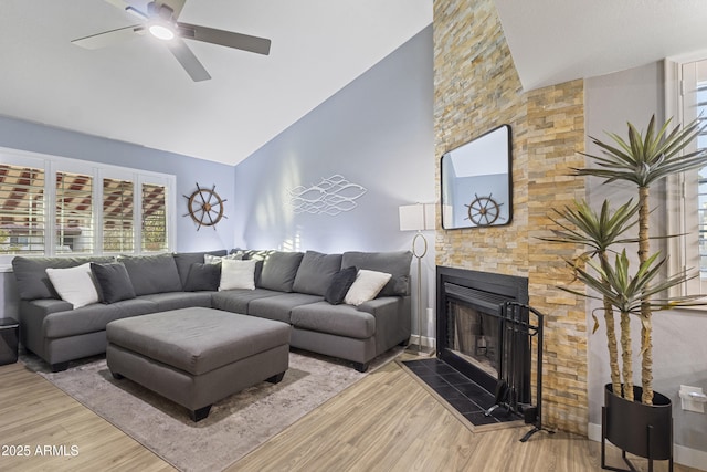 living room featuring ceiling fan, hardwood / wood-style floors, high vaulted ceiling, and a fireplace