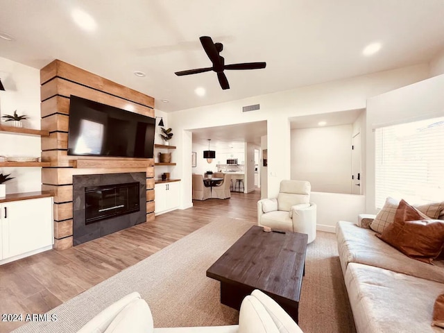 living room featuring a tiled fireplace, ceiling fan, and hardwood / wood-style floors