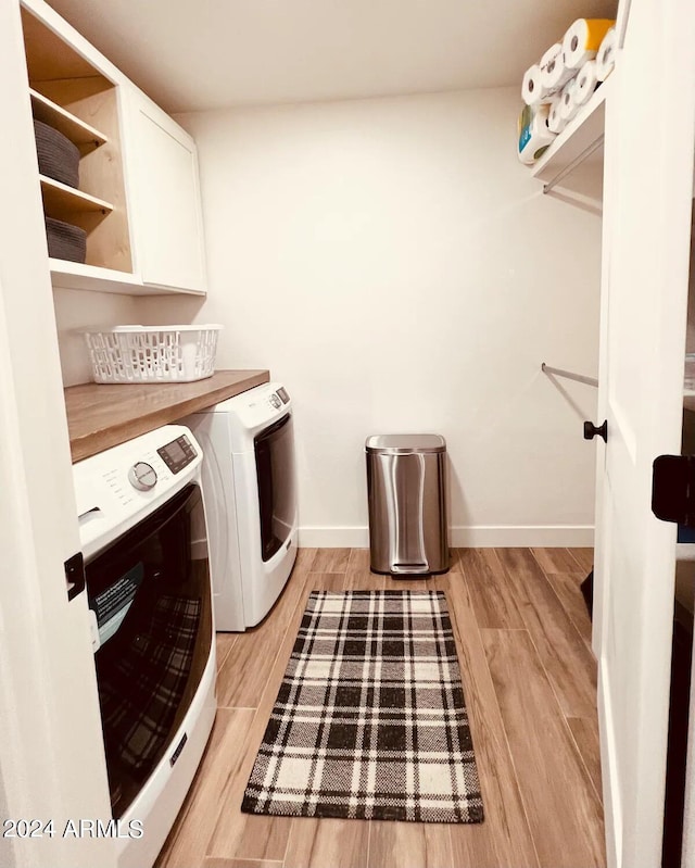 washroom with cabinets, separate washer and dryer, and light wood-type flooring