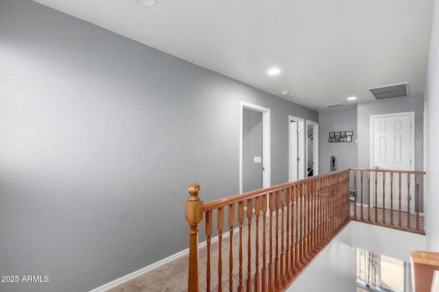 corridor with carpet flooring, an upstairs landing, visible vents, and baseboards