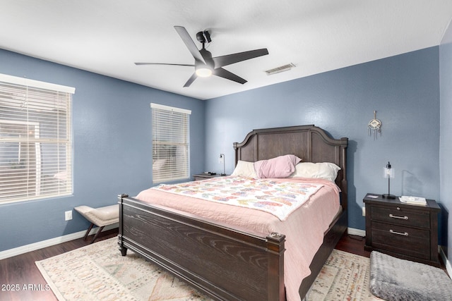 bedroom with ceiling fan, wood finished floors, visible vents, and baseboards