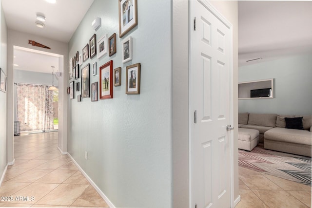 hallway with light tile patterned floors, visible vents, and baseboards