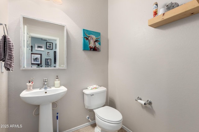 half bathroom featuring a sink, baseboards, and toilet