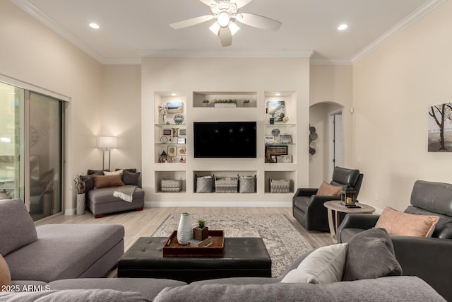 living room featuring arched walkways, ornamental molding, light wood-type flooring, and built in shelves