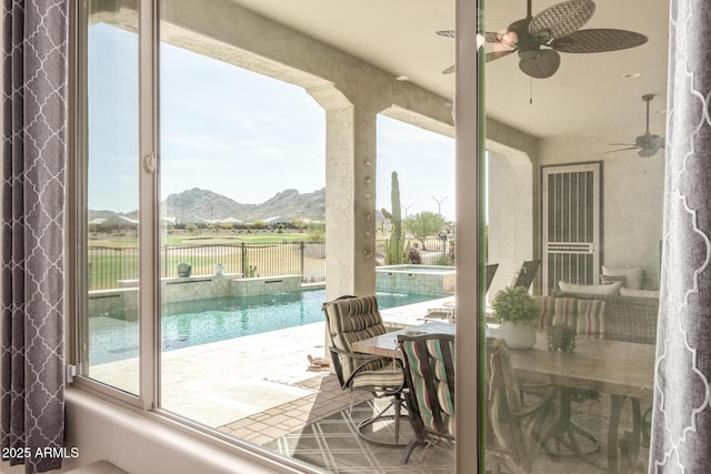 exterior space featuring a pool with connected hot tub, ceiling fan, fence, and a mountain view