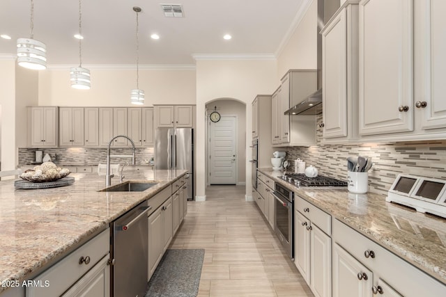 kitchen with arched walkways, crown molding, visible vents, appliances with stainless steel finishes, and a sink