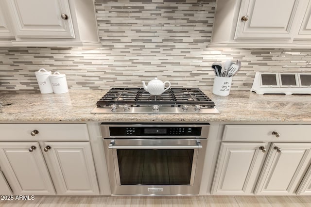 kitchen featuring stainless steel appliances, white cabinets, and backsplash