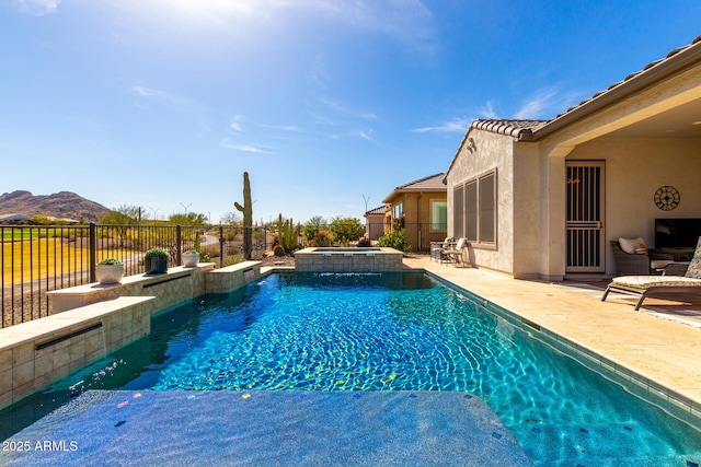 view of swimming pool featuring a patio area, a pool with connected hot tub, fence, and a mountain view