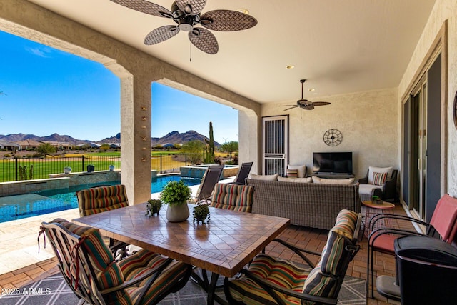 view of patio / terrace featuring a fenced backyard, an outdoor hangout area, a pool with connected hot tub, a ceiling fan, and outdoor dining space