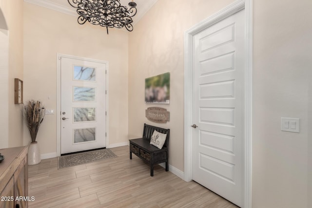 entrance foyer featuring arched walkways, a notable chandelier, baseboards, light wood-type flooring, and crown molding