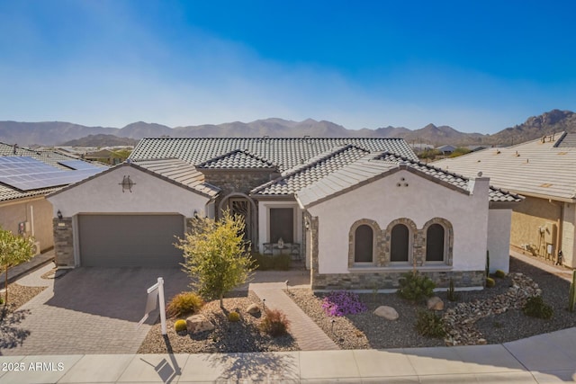 view of front facade featuring an attached garage, stone siding, a tile roof, and a mountain view