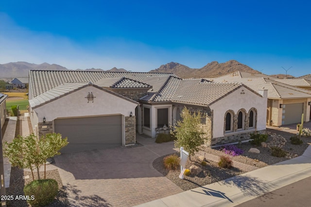 mediterranean / spanish-style house featuring stone siding, a mountain view, and a tiled roof