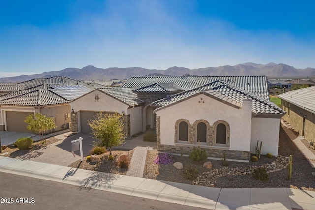 view of front of house featuring a tile roof, an attached garage, decorative driveway, a mountain view, and stucco siding