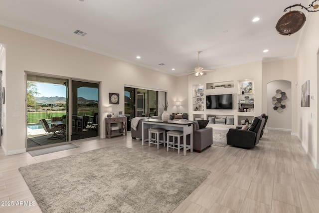 living area with built in features, arched walkways, visible vents, ornamental molding, and baseboards