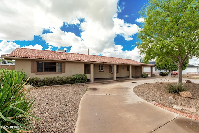 ranch-style house with concrete driveway, a tiled roof, an attached garage, and stucco siding