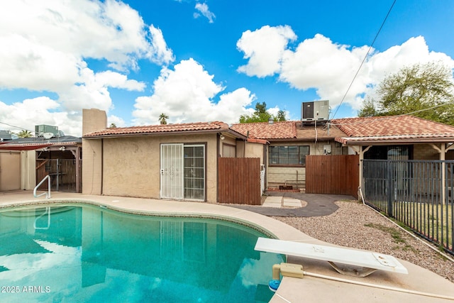 view of swimming pool with cooling unit, a fenced in pool, fence, a diving board, and a patio area