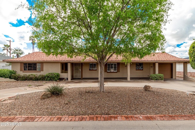 single story home with a tiled roof, stucco siding, driveway, and a garage