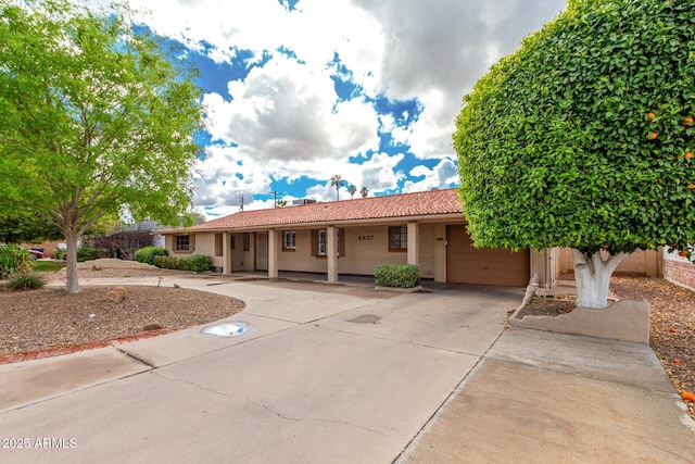 ranch-style home featuring a tile roof, stucco siding, and concrete driveway