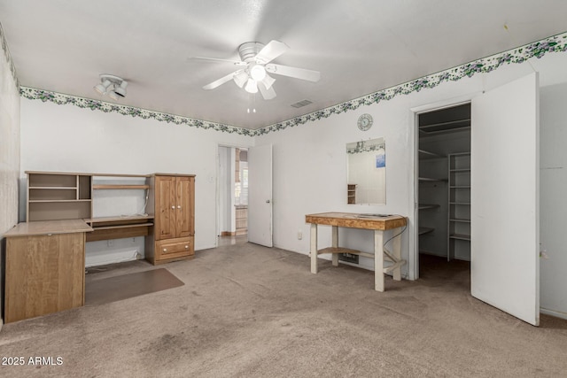 unfurnished bedroom with ceiling fan, visible vents, light carpet, and a walk in closet