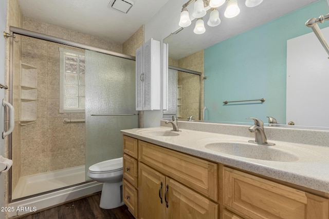 full bath featuring wood finished floors, a stall shower, toilet, and a sink