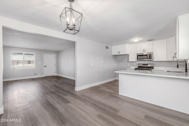 kitchen with sink, decorative light fixtures, white cabinetry, appliances with stainless steel finishes, and light hardwood / wood-style floors