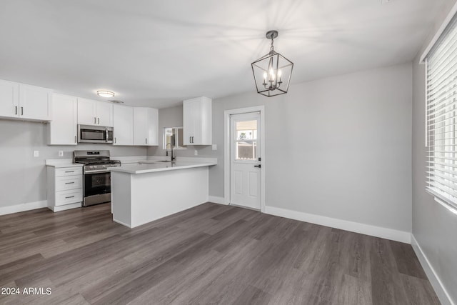 kitchen with appliances with stainless steel finishes, kitchen peninsula, white cabinets, and hanging light fixtures