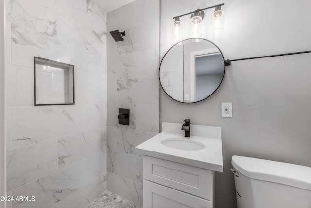 bathroom featuring toilet, vanity, and a tile shower