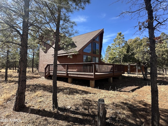 view of side of home featuring roof with shingles and a deck