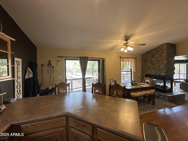 kitchen with a ceiling fan, lofted ceiling, open floor plan, and wood finished floors
