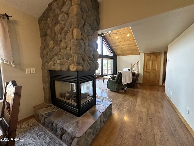 sitting room featuring wood finished floors, ceiling fan, baseboards, a fireplace, and lofted ceiling