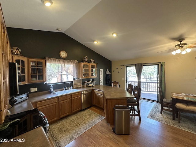 kitchen with stainless steel dishwasher, a sink, glass insert cabinets, light wood-type flooring, and a peninsula