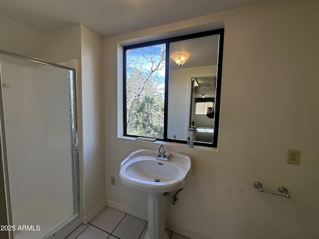 bathroom with a shower stall, tile patterned flooring, baseboards, and a sink