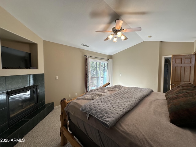 carpeted bedroom featuring a tiled fireplace, baseboards, visible vents, lofted ceiling, and a ceiling fan