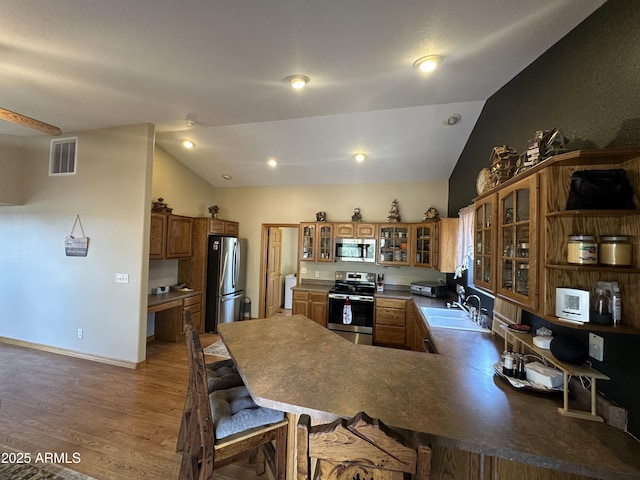 kitchen featuring a sink, visible vents, lofted ceiling, wood finished floors, and appliances with stainless steel finishes