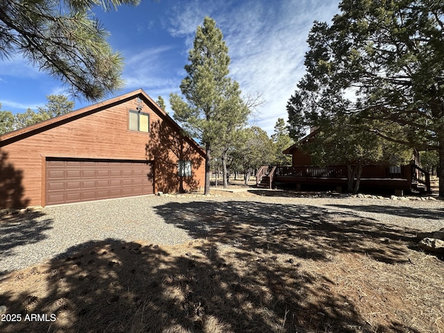 view of side of home with driveway, a deck, and a garage