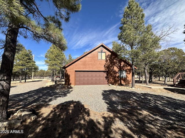 view of property exterior with a garage and gravel driveway
