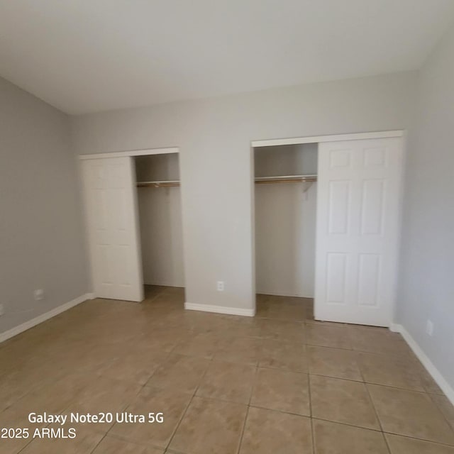 1829 E Adams St, Phoenix, AZ 85034 - unfurnished bedroom with two closets, light tile patterned flooring, and baseboards