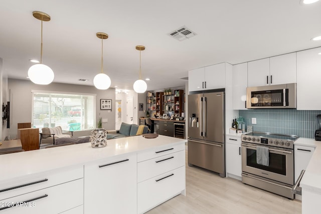 kitchen with appliances with stainless steel finishes, decorative light fixtures, tasteful backsplash, white cabinetry, and wine cooler